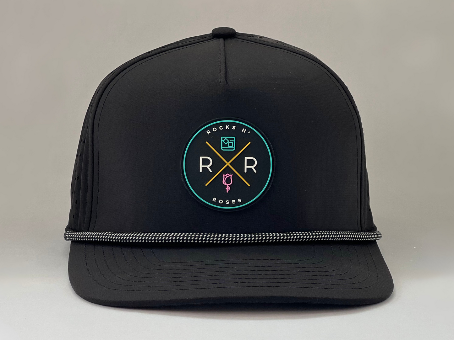 Image of a black golf hat made from polyester with a teal, pink, and gold rubber Rocks N' Roses logo and a black and white gridline rope accent.
