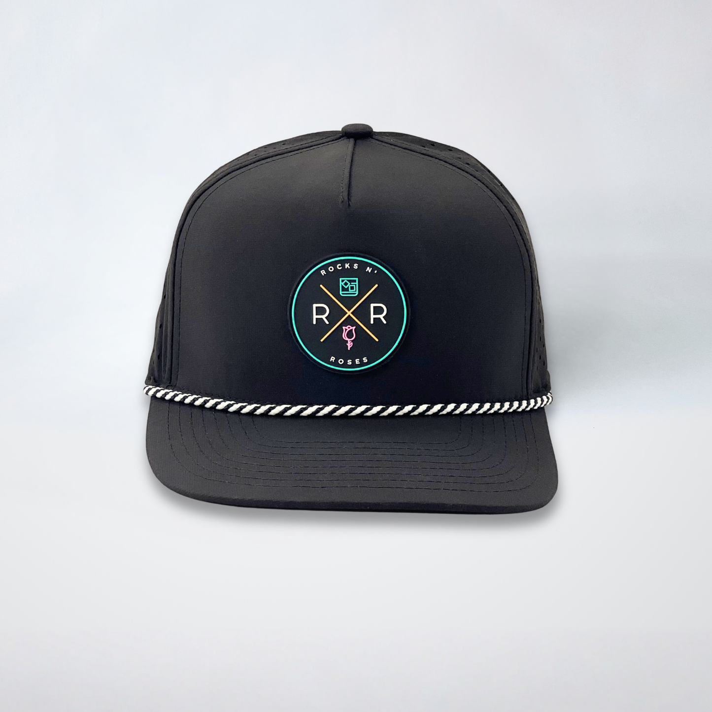 Image of a black golf hat with a teal, pink, and gold rubber Rocks N' Roses logo and a black and white diagonal rope accent.