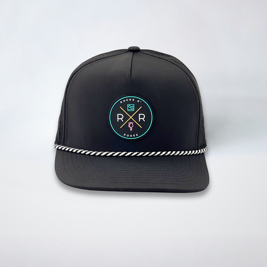Image of a black golf hat with a teal, pink, and gold rubber Rocks N' Roses logo and a black and white diagonal rope accent.