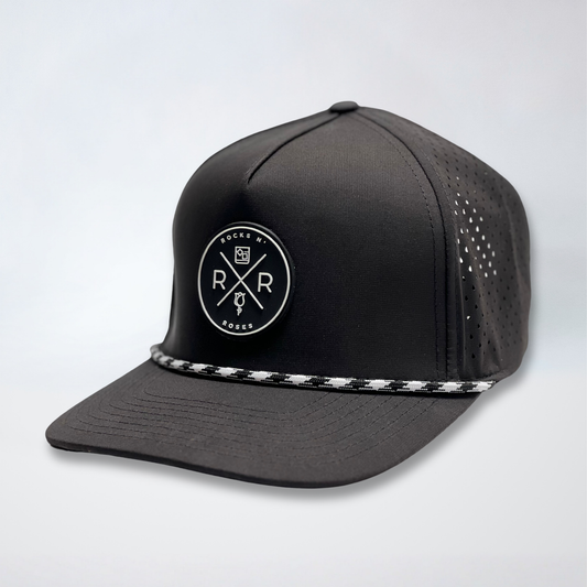 product phograph of the Rocks N' Roses Black Performance Golf Hat. This 100% polyester snapback hat is water resistant, offers some stretch and has that new school flat brim look. Also, it features a rubber logo and black and white rope that decorates the front brim. Laser cut venting for max breathability.
