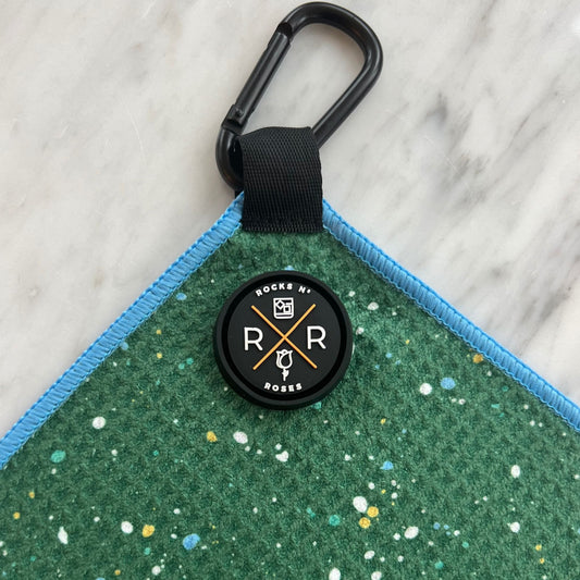 Close up photo of the Rocks N' Roses magnetic golf towel in green with a fun paint splatter pattern. Close up shows waffle towels texture and magnet / carabiner for attaching to your golf bag or golf cart.