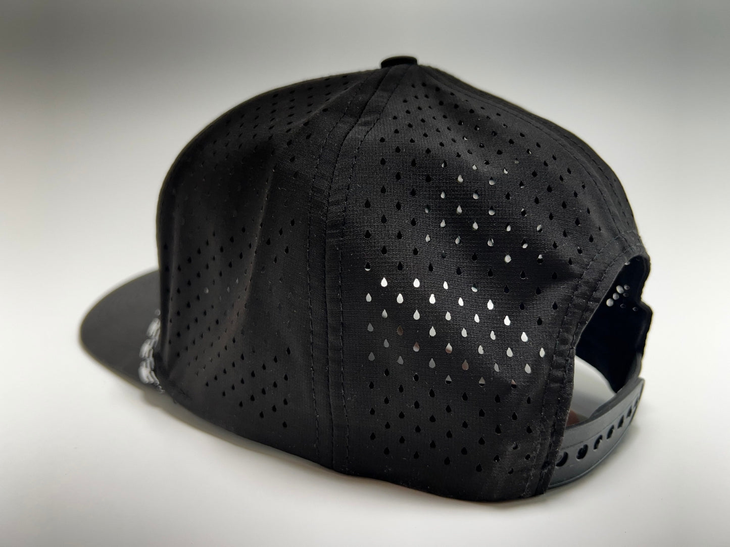 An image showing the back of the Rocks N' Roses performance black golf hat. In the image we see the back panels of the hat which feature laser cut vents for maximum breathability as well as an adjustable snapback.