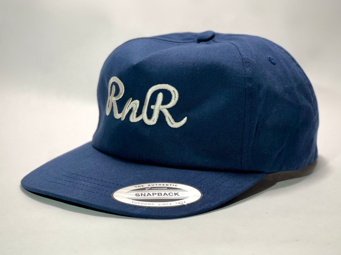Rocks N' Roses navy blue flat brim golf hat featuring a white cursive RNR embroidered logo.