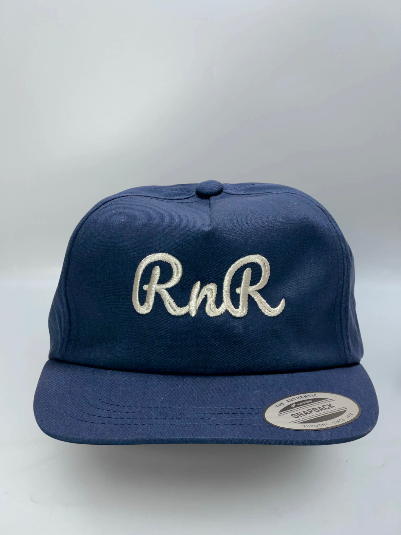 Rocks N' Roses navy blue flat brim golf hat with embroidered RNR cursive logo in white.
