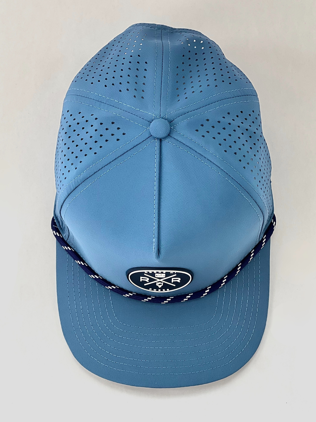 Rocks N' Roses Polyester Blue Steel Golf Hat overhead photograph showing laser perforated back panels navy blue and white rubber logo and navy blue and white decorative rope.