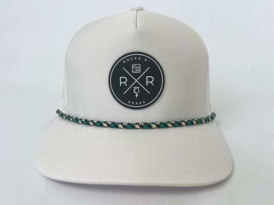 Image of the Rocks N' Roses 5 panel white golf hat. This performance hat is made of 100% polyester and is water resistant and has some stretch. It features a black and white circular rubber logo on the front and a black, white, and teal checkered rope.