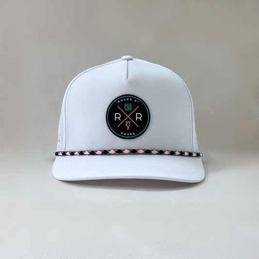 Image of a white golf hat made from 100% polyester with a teal, pink, and gold rubber Rocks N' Roses logo and a pink and black diamond rope.