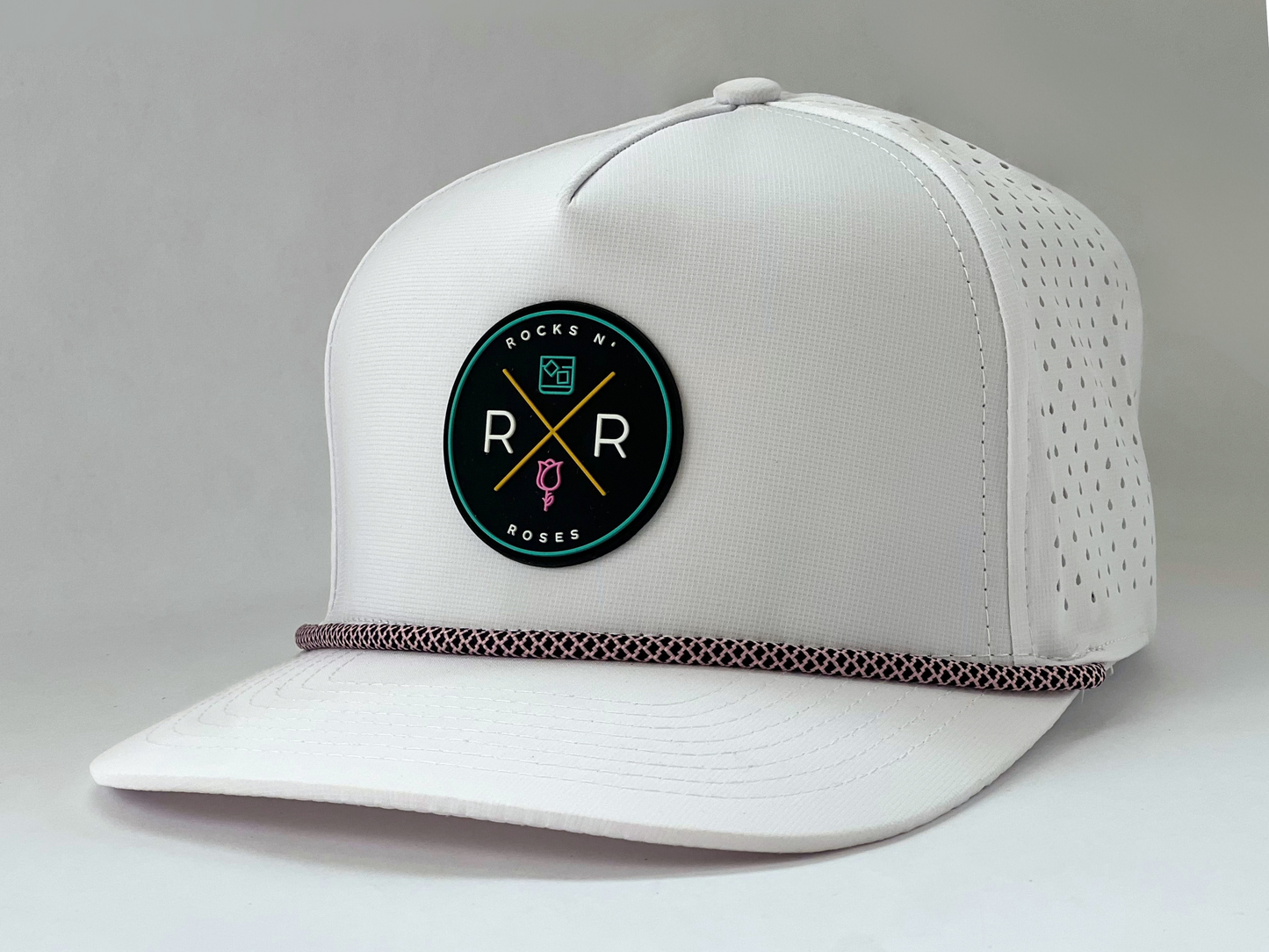 Side shot of the Rocks N' Roses Tropical Sunset White Women's Golf Hat. This performance golf hat features rubber logo on front and pink and black rope.
