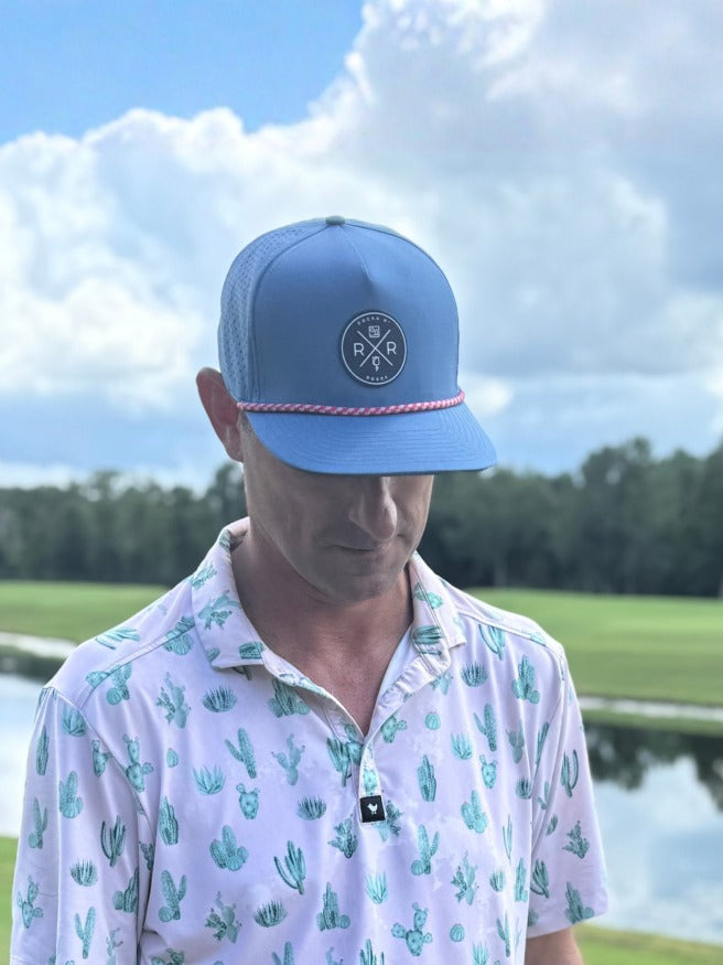 Model wearing the Rocks N' Roses Blue Steel golf hat featuring a navy blue and white rubber logo and red, white, and blue accent rope.