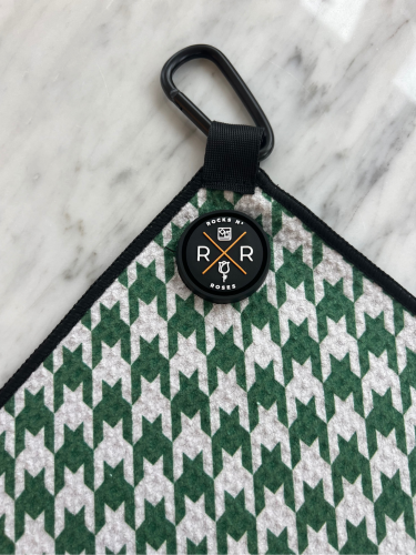 Close up shot of the Rocks N' Roses magnetic golf towel in a green and white houndstooth pattern. Close up shows the magnet and carabiner for attaching to your golf bag.