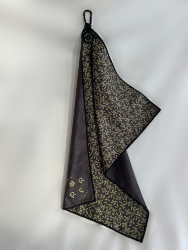 An image of the Rocks N' Roses Magnetic Golf Towel. On one side this magnetic golf towel has a black background with a golf floral pattern. The opposite side is plain black with a gold Rocks N' Roses logo in the bottom corner. 