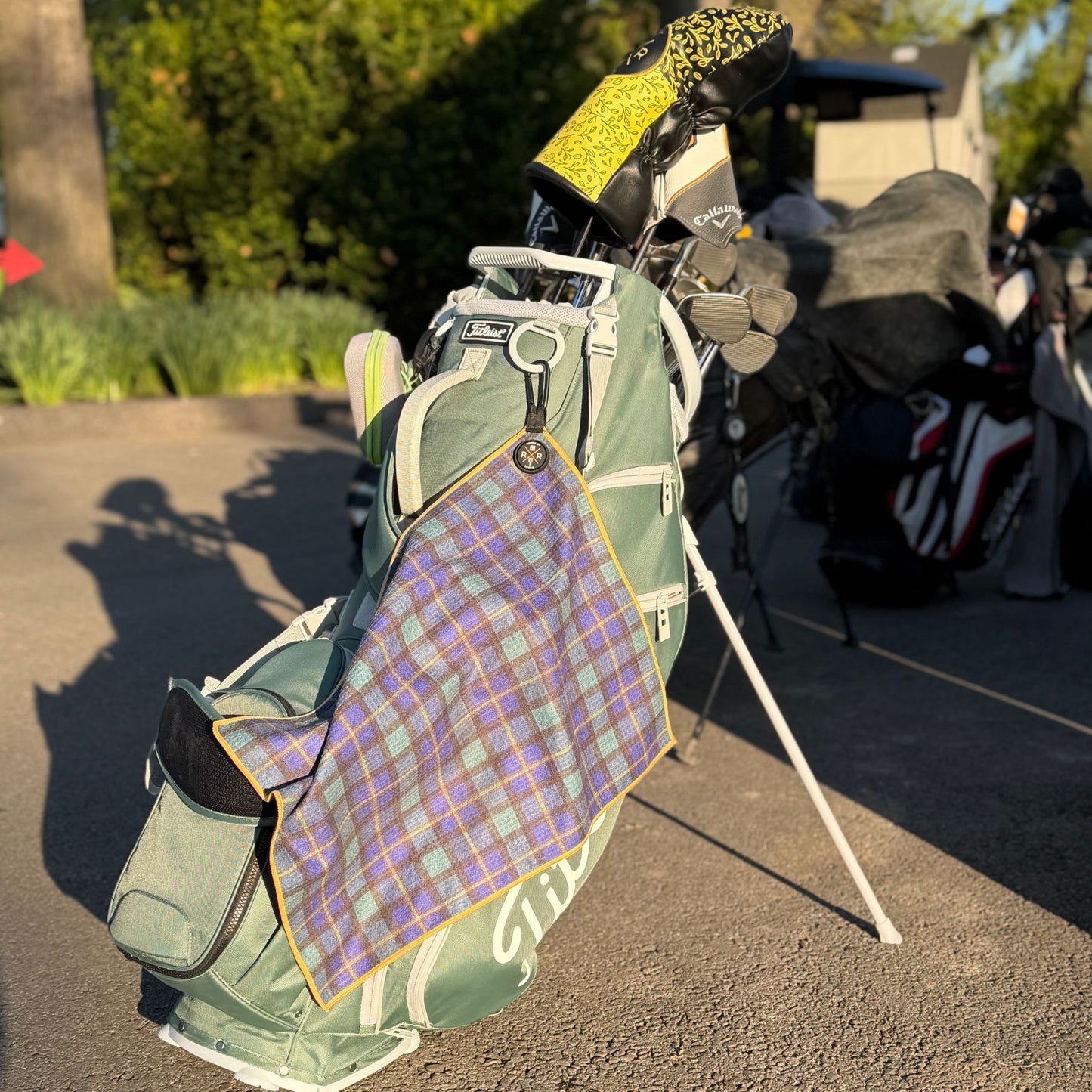 Premium tartan magnetic golf towel with carabiner attached to golf bag on course featuring plaid design and quick-access magnetic functionality.