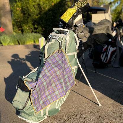 Premium tartan magnetic golf towel with carabiner attached to golf bag on course featuring plaid design and quick-access magnetic functionality.