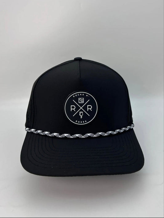 Image of the Rocks N' Roses 5 panel black golf hat. This performance hat is made of 100% polyester and is water resistant and has some stretch. It features a black and white circular rubber logo on the front and a black and white rope.