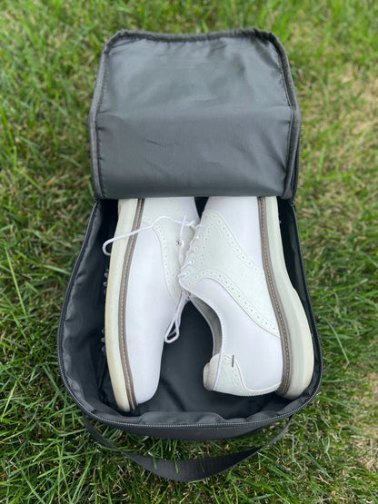 An image of a pair of white saddle golf shoes inside of the Rocks N' Roses black waterproof golf shoe bag.