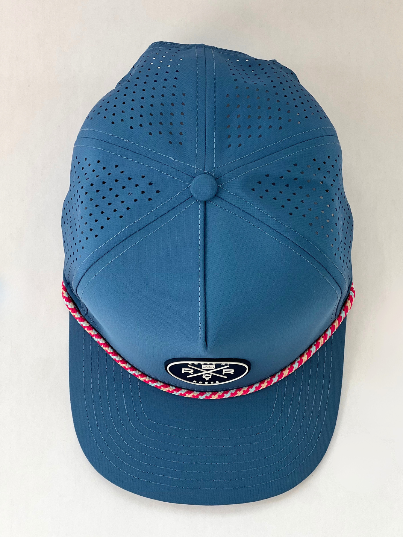 Rocks N' Roses Polyester Blue Steel Golf Hat overhead photograph showing laser perforated back panels, navy blue and white rubber logo and red, white and blue decorative rope.