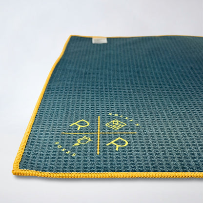 Close up photo showing a waffle weave golf towel part of the Rocks N' Roses Magnetic Golf Towel collection. Teal and blue tartan pattern with yellow gold.