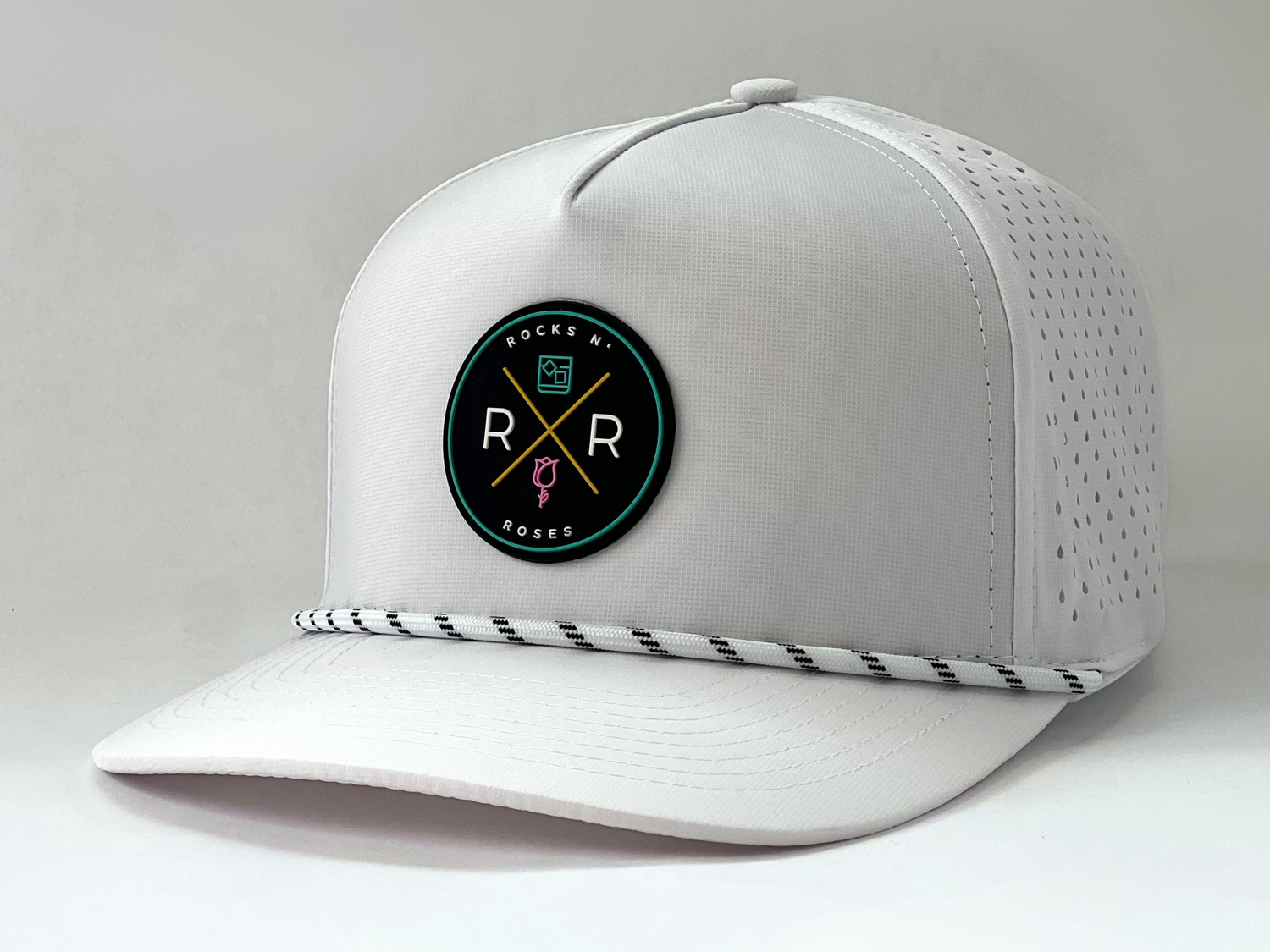 side shot of the Rocks N' Roses Tropical Sunset Golf Hat in White. This performance golf hat features a multi-color rubber logo and white rope with black accents.