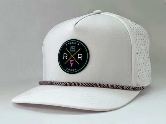 Side shot of the Rocks N' Roses Tropical Sunset White Women's Golf Hat. This performance golf hat features rubber logo on front and pink and black rope.