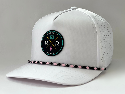 The new Rocks N' Roses Tropical Sunset Women's Golf Hat in White featuring a teal, pink, gold, white and black logo as well as a pink and black diamond rope.
