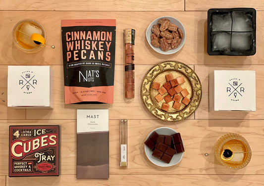 The Rocks N' Roses Bourbon Box featuring two RNR spinning whiskey glasses, Nat's Nuts cinnamon whiskey pecans, Mast Brother's dark chocolate bar, Yes Cocktail Co.'s 5 spice Old Fashioned sugar cubes, Trixie & Milo's Xtra large ice cube tray, and Luxe's cocktail spears.